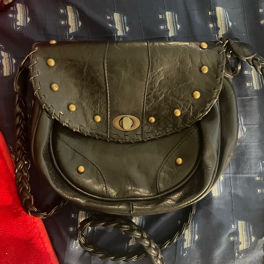 Small black purse with shoulder strap. Has gold studs on the front